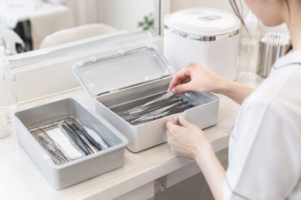 サロンの洗面台で、女性が消毒済みの器具をケースから取り出している