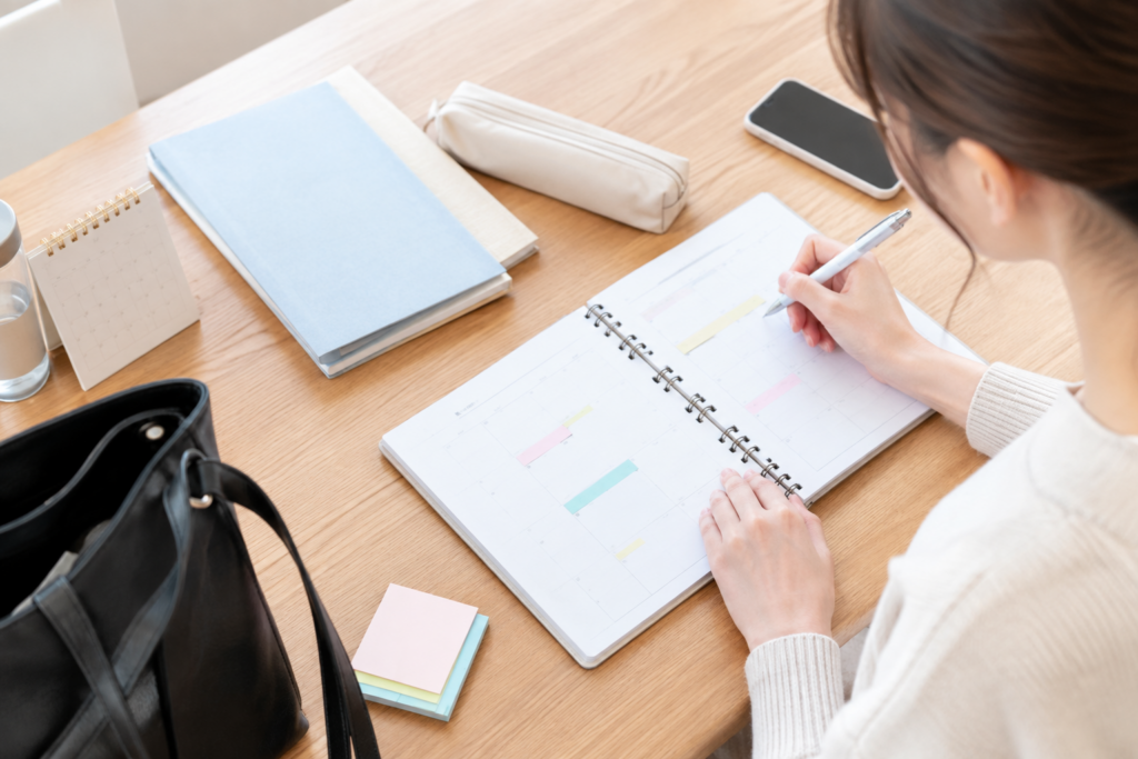 机で手帳に予定を書き込む女性