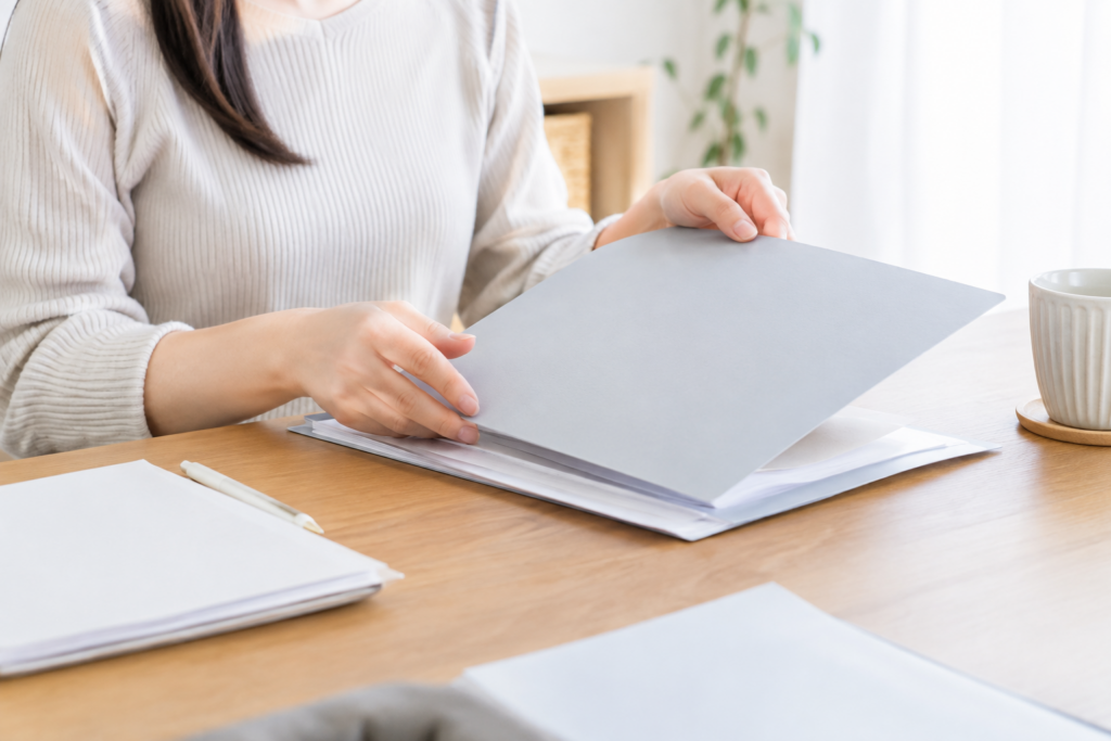 机の上で書類をめくりながら確認している女性の手元