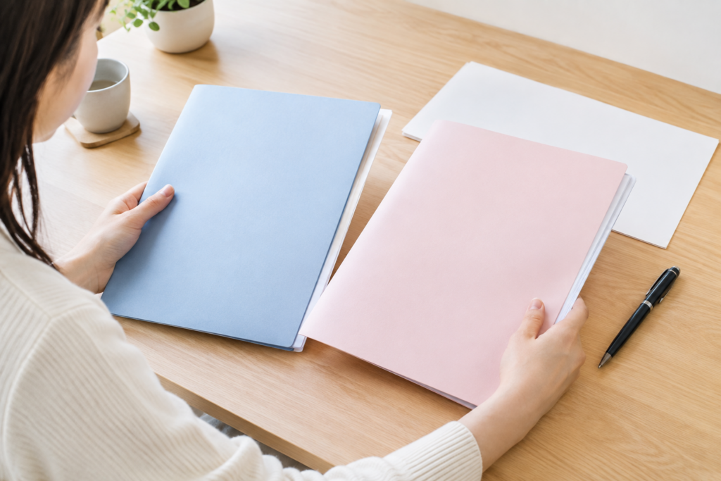 机の上でノートや書類を見比べる人物の手元