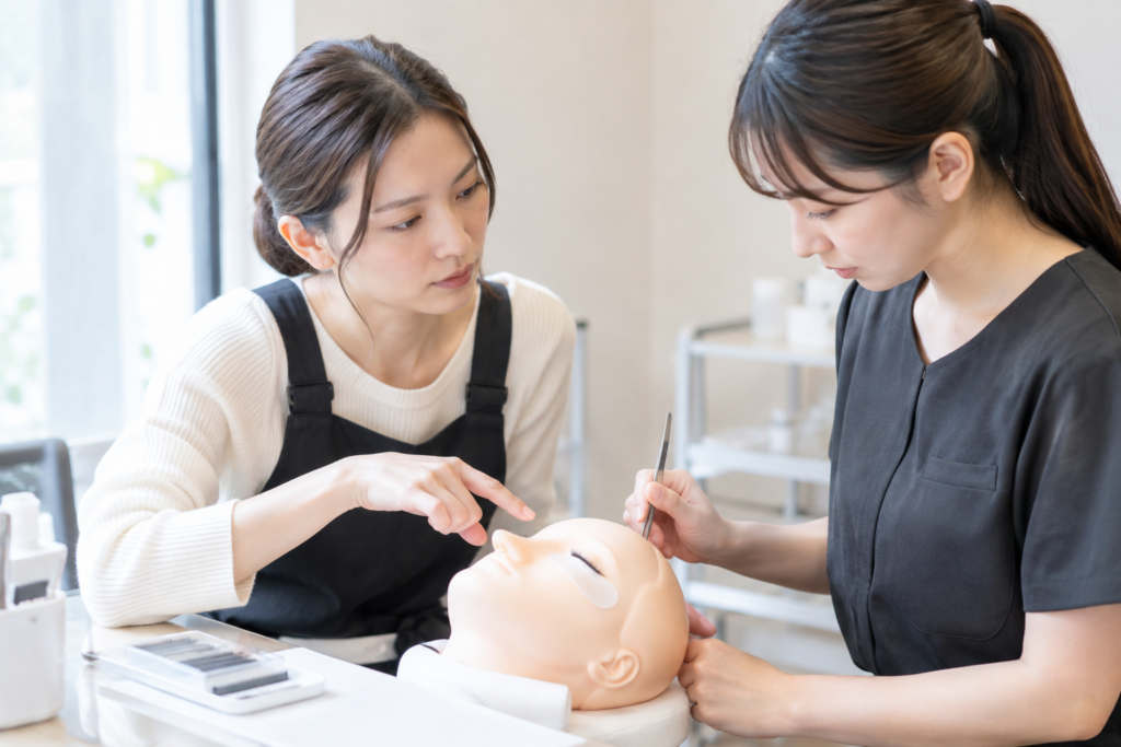 美容室で2人の女性が施術用の人形を使って研修している様子