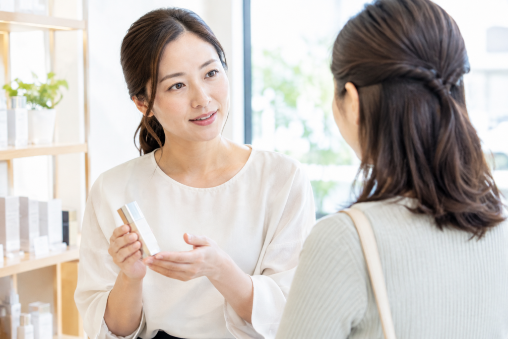 美容サロンで女性スタッフが客に商品を見せながら説明している